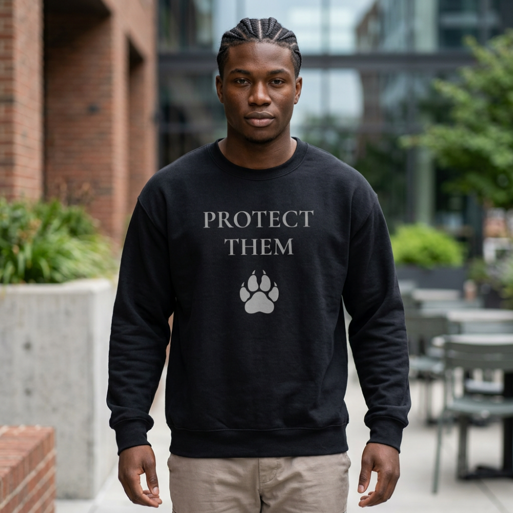 A man wearing a black crewneck sweatshirt with the text 'PROTECT THEM' and a paw print graphic in gray, standing outdoors in front of a brick building.
Details