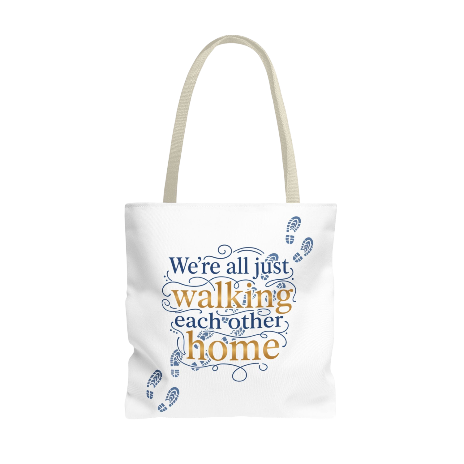 A white canvas tote bag with beige handles, featuring a printed graphic on the front that reads 'We're all just walking each other home' in navy blue and mustard yellow lettering, accented with small blue footprint illustrations.