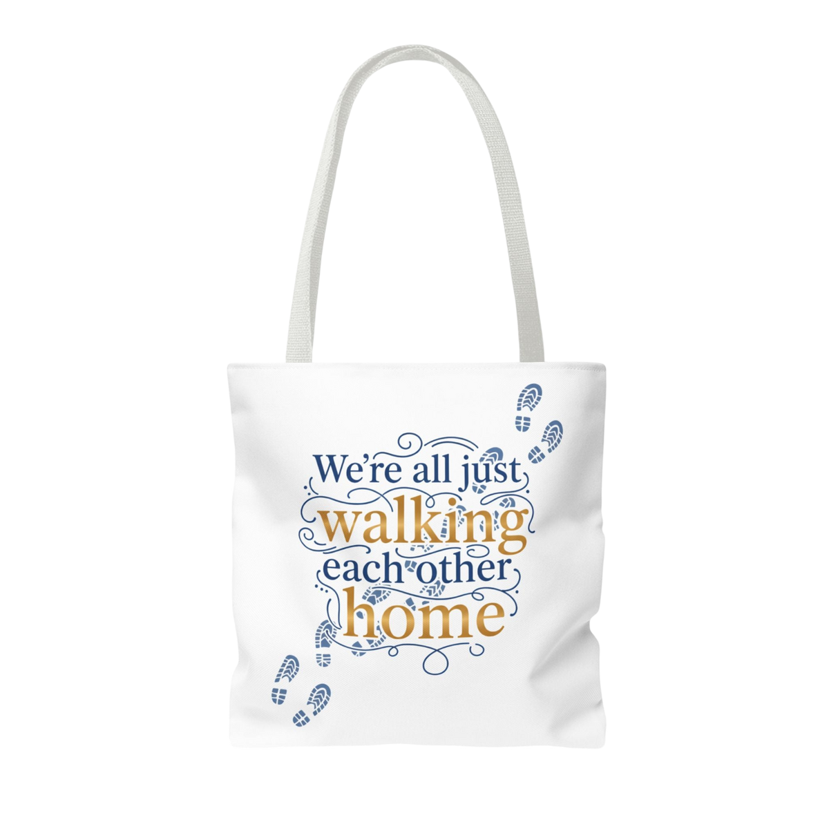A white canvas tote bag with white shoulder straps, featuring a printed graphic on the front. The graphic displays the phrase 'We're all just walking each other home' in blue and orange lettering, decorated with blue baby footprints.