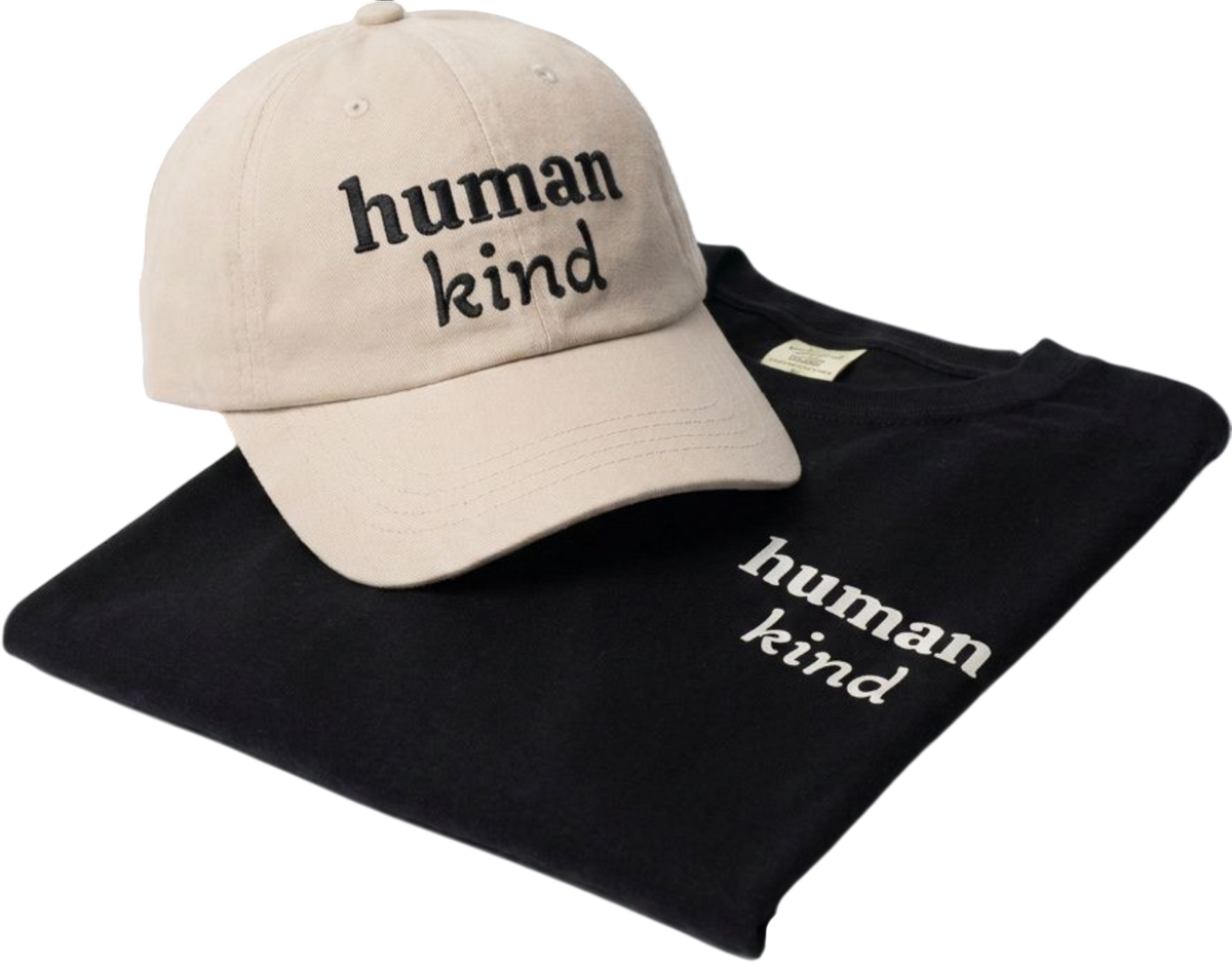 A beige baseball cap with black embroidered text reading 'human kind' resting on top of a folded black T-shirt with white embroidered text reading 'human kind' on a white background.