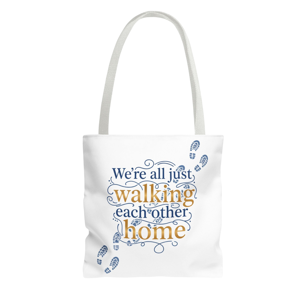 A white canvas tote bag with a printed quote that reads 'We're all just walking each other home' in blue and gold lettering, decorated with blue footprints, shown against a plain white background.