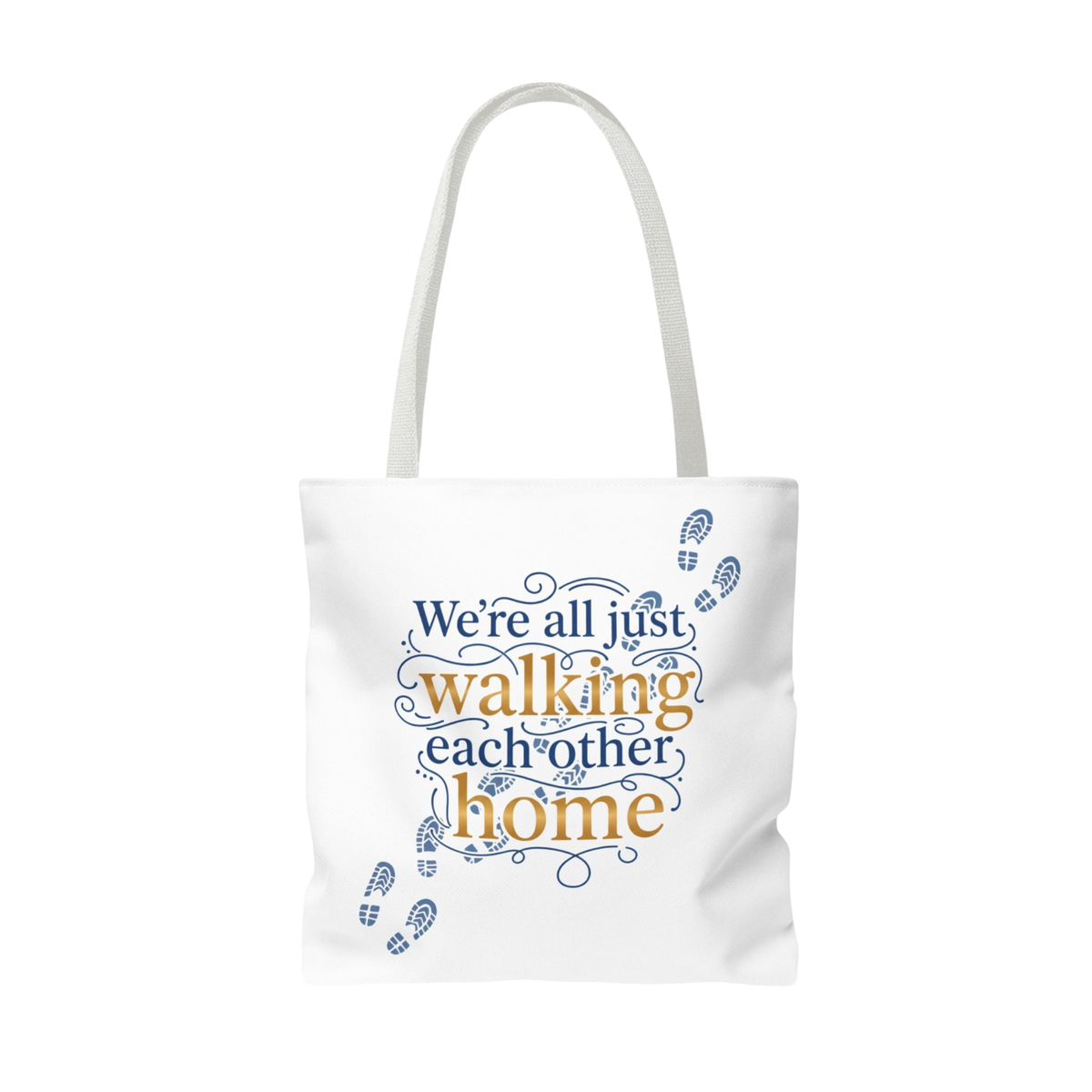 A white canvas tote bag with white shoulder straps, featuring a printed graphic on the front that reads 'We're all just walking each other home' in blue and orange lettering, decorated with blue footprint illustrations.