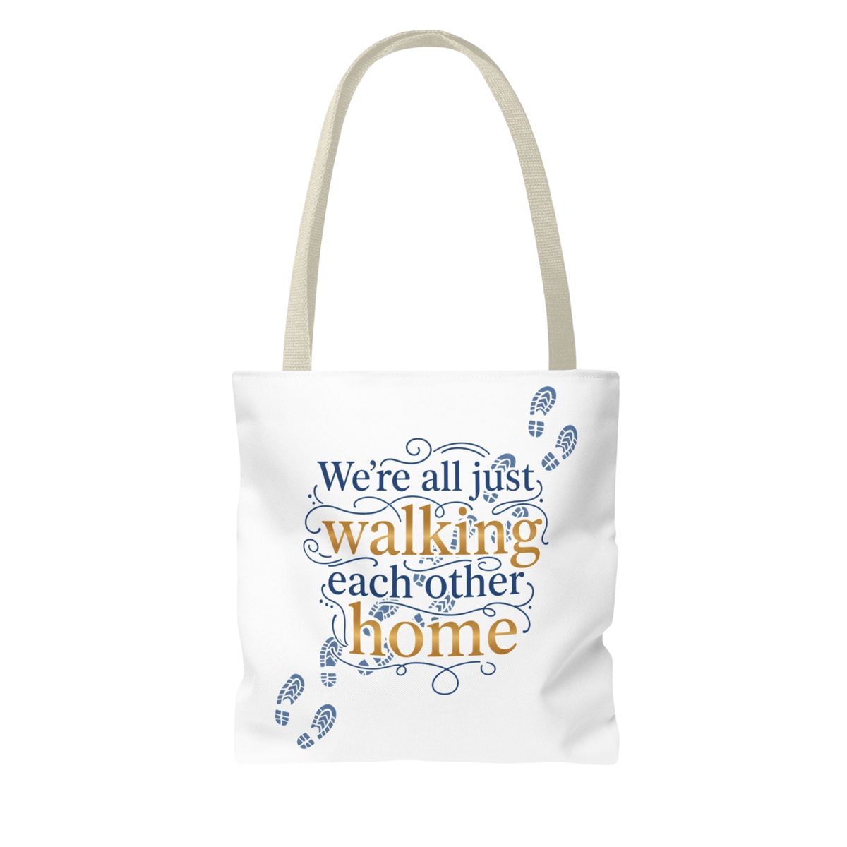 A white canvas tote bag with beige handles, featuring a printed graphic on the front that reads 'We're all just walking each other home' in blue and gold lettering, accented with blue footprint illustrations.