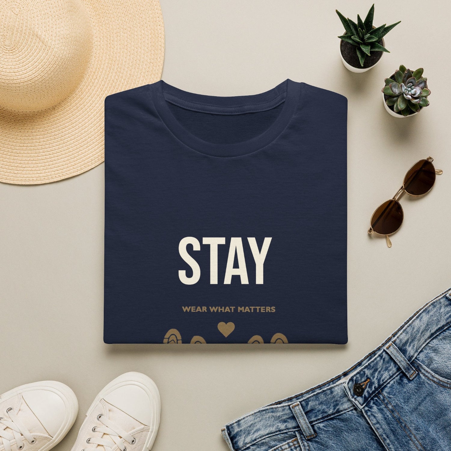 Dark gray t-shirt with white plant design, surrounded by a hat, sunglasses, shoes,
