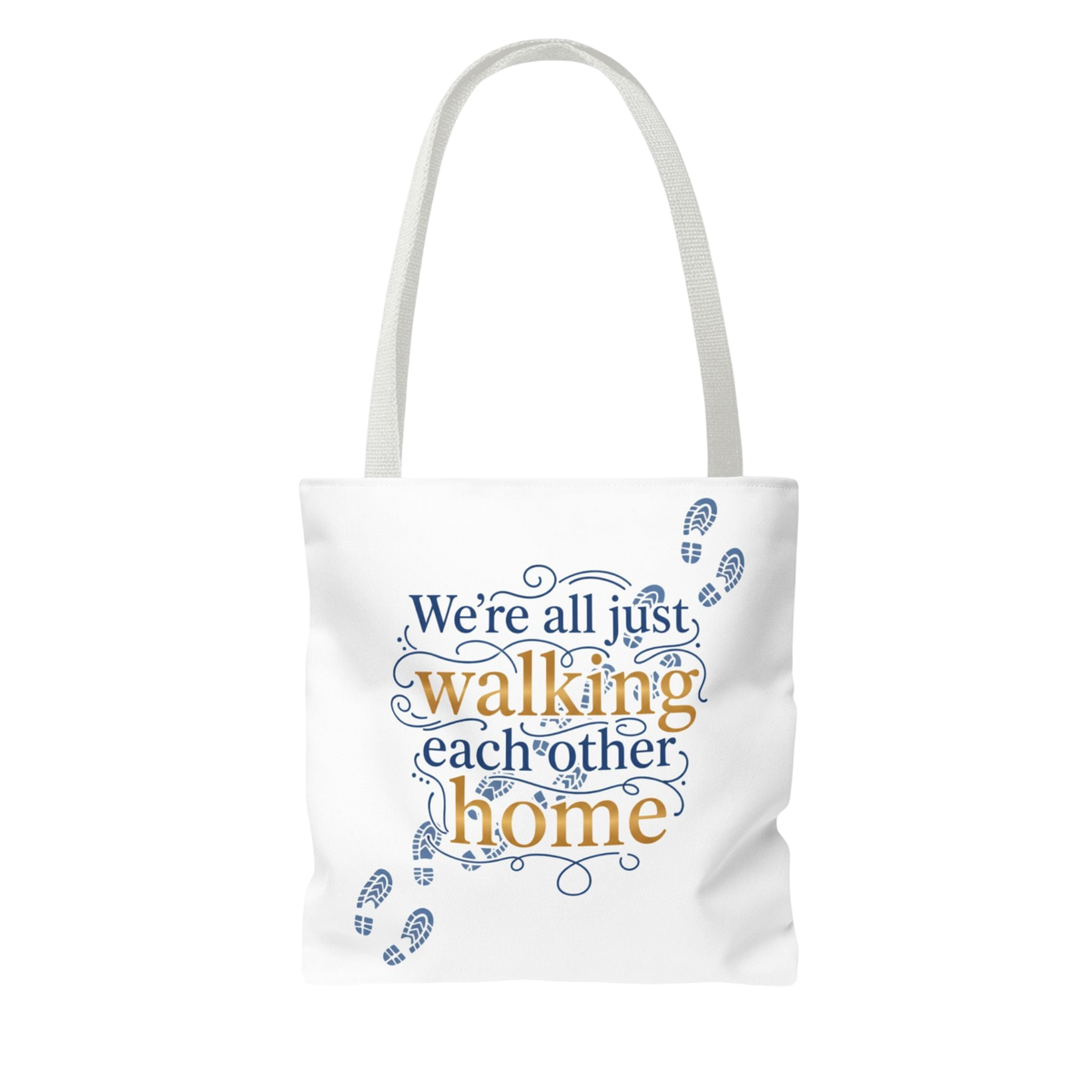 A white canvas tote bag with a double shoulder strap, featuring a printed graphic on the front that reads 'We're all just walking each other home' in blue and gold lettering, decorated with blue footprint illustrations.
