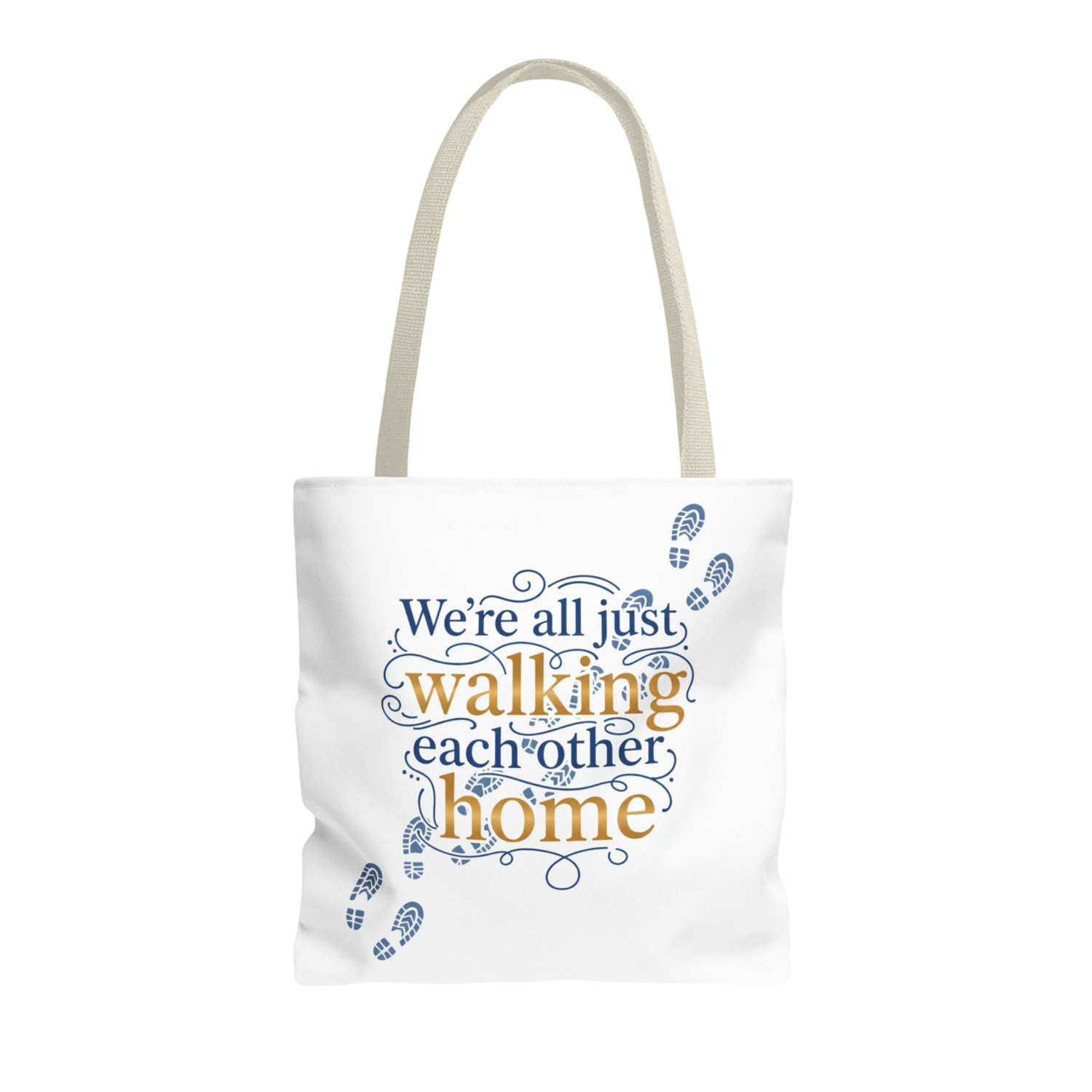 A white canvas tote bag with beige shoulder straps, featuring a printed quote that reads 'We're all just walking each other home' in blue and orange lettering, accented with blue footprints, on a plain white background.