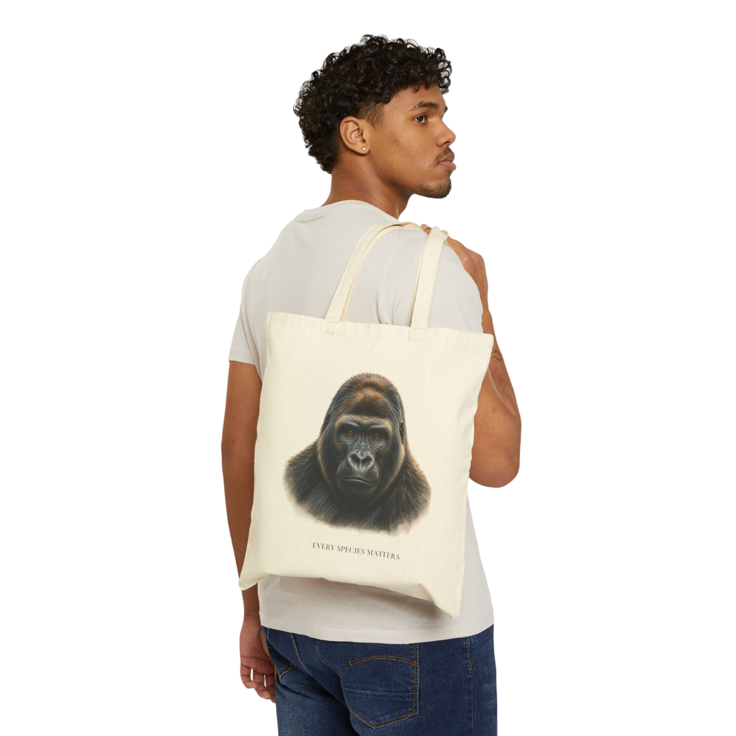 A man wearing a white t-shirt and blue jeans is shown from the back, carrying a cream canvas tote bag over his shoulder. The tote bag features a detailed graphic print of a gorilla's face with the text 'EVERY SPECIES MATTERS' printed below.