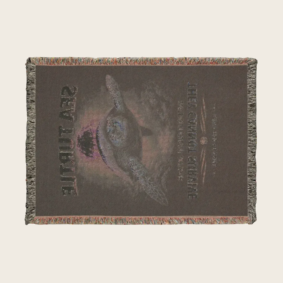 A rectangular woven throw blanket with fringe edges, featuring a sea turtle design and the words 'SEA TURTLE' and 'THE CROWNED CRUISE' on a dark brown background.
