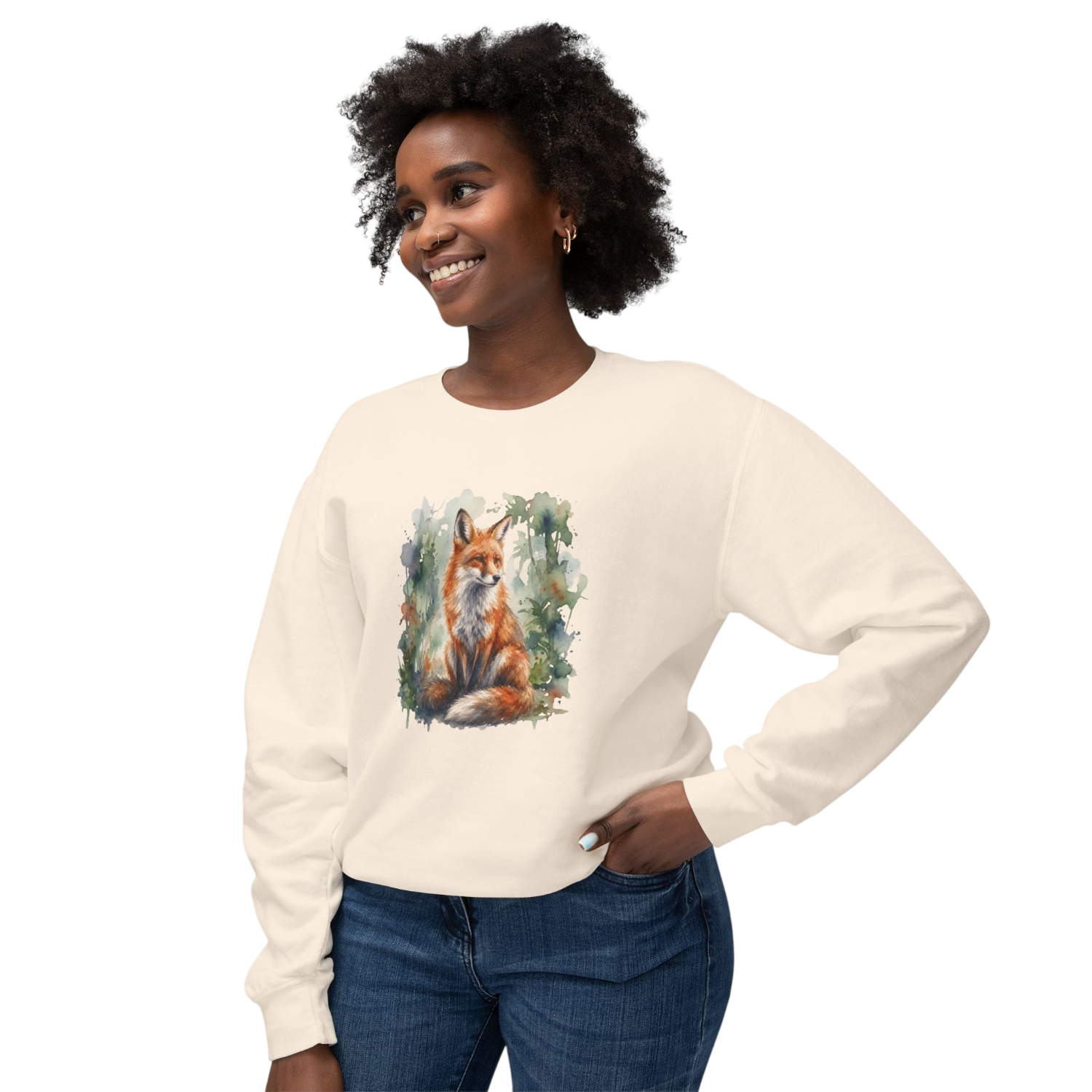 A woman wearing a cream-colored long-sleeve crewneck sweatshirt with a watercolor-style graphic of a red fox in a forest on the front, paired with blue jeans, set against a plain white background.